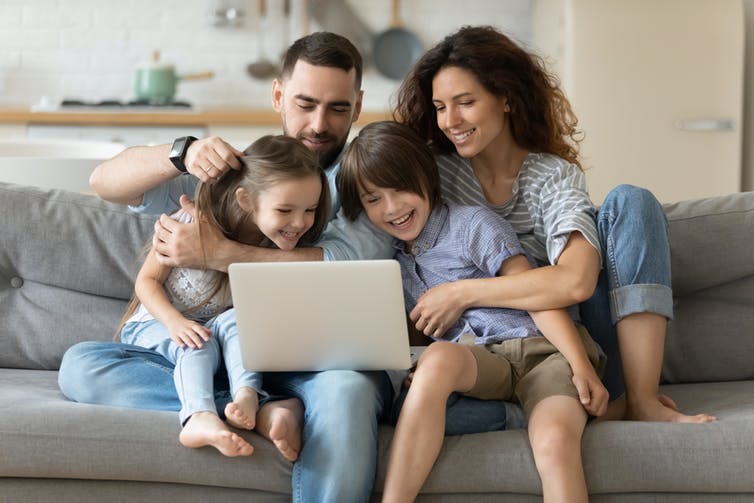 A family of four look at a laptop.