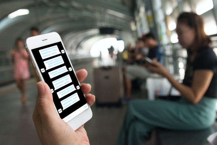 A person holding a phone showing a chat.