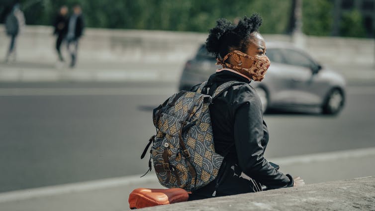 A woman observes her surroundings outside.