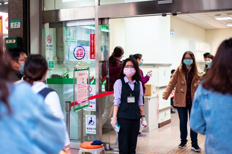 A Taiwanese postal worker holding a thermometer.