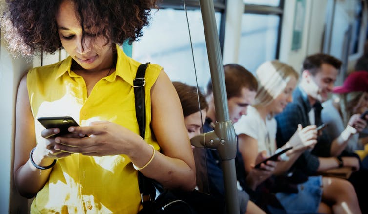 A woman on public transport using her phone.