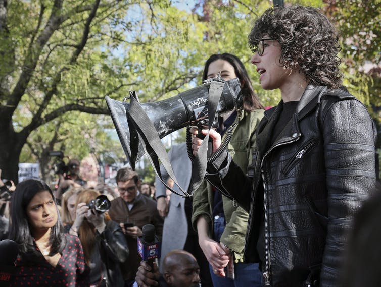 A woman with curly hair speaks into a megaphone.