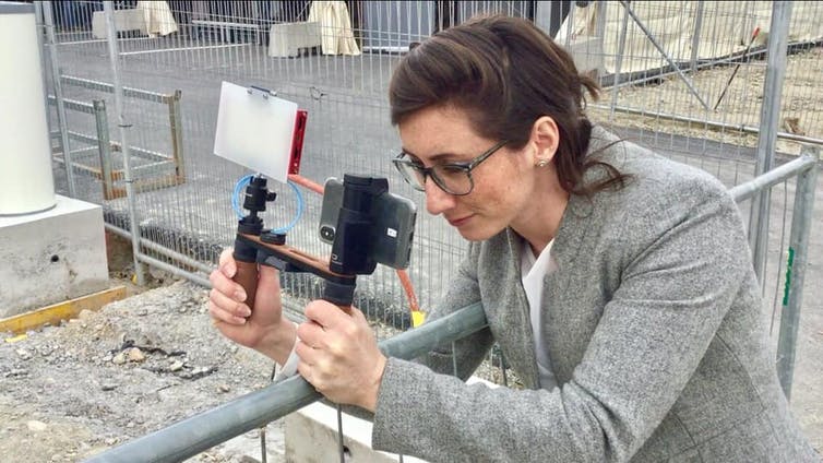 A journalist with a video camera setting up a shoot.