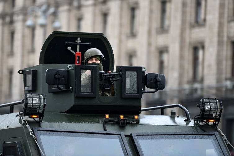 A soldier wearing a helmet peeks out of a tank.