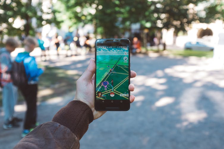 Hand holding up phone playing Pokémon Go