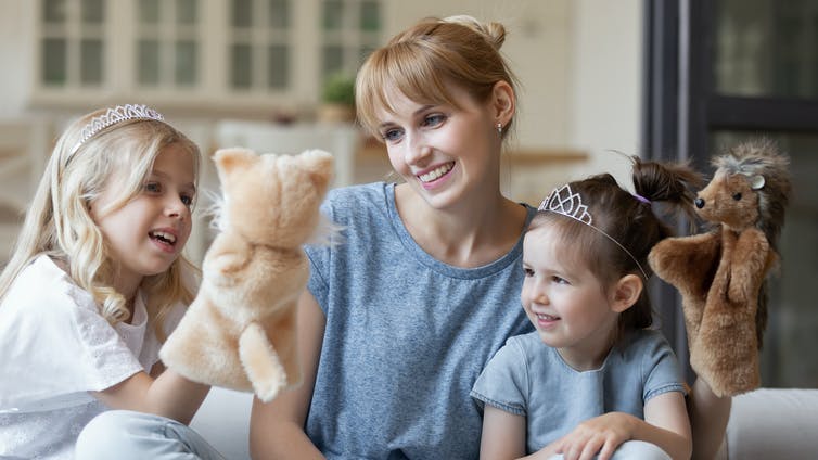 Mother and two daughters talking using puppets.