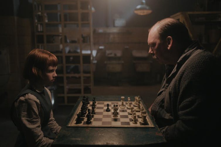 A girl and man playing chess.