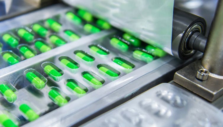 Blister packs of green capsules being made in a factory