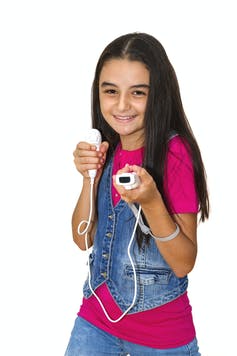 A young teenager in a pink t-shirt and denim waistcoat holding a Wii controller.