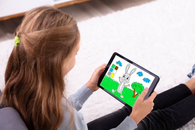 Side profile of a young girl holding a tablet with a cartoon rabbit on the screen