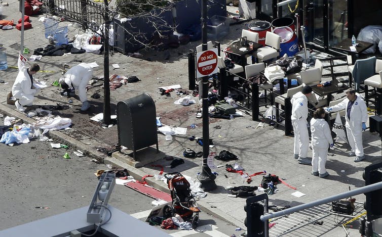 Investigators in white suits examining the bombing scene at the Boston Marathon.