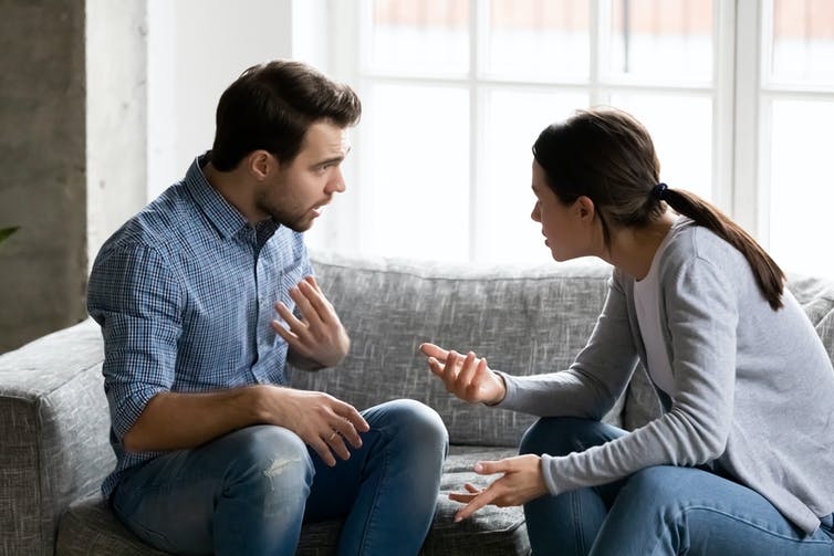 A woman and man argue sitting on a couch.