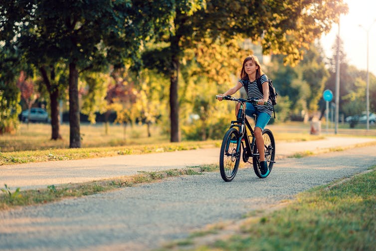 girl rides bike through park