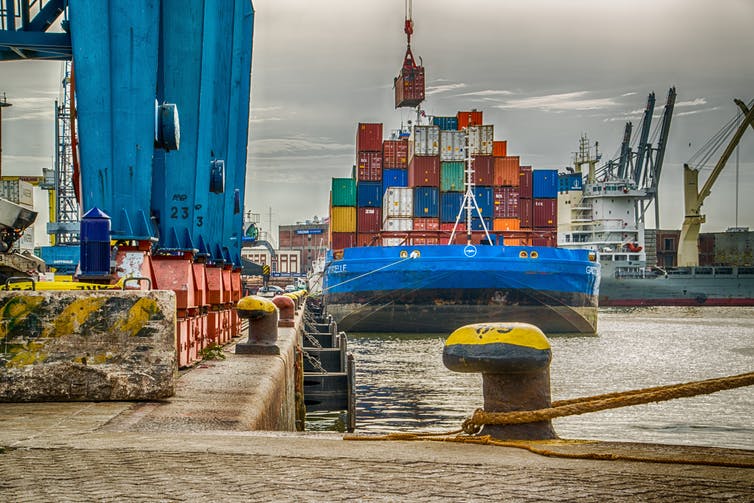 Cranes load shipping containers onto a ship docked in port.