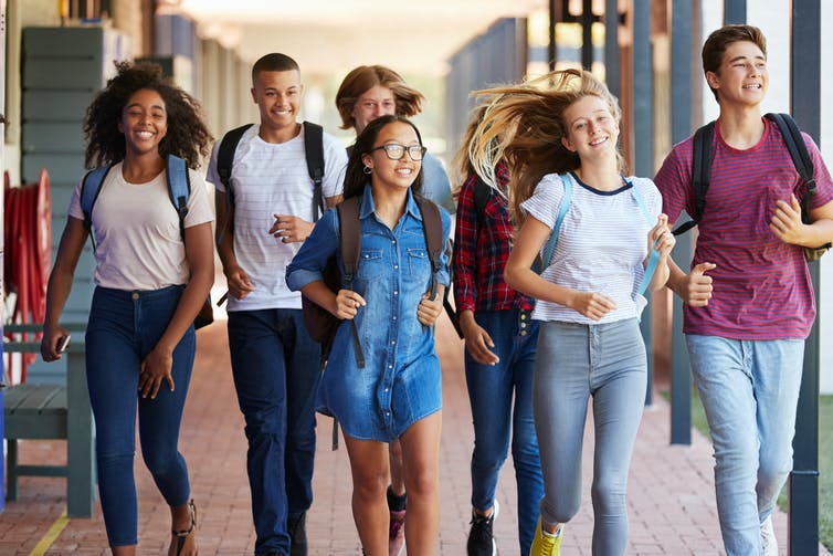 Seven children running down a school hallway