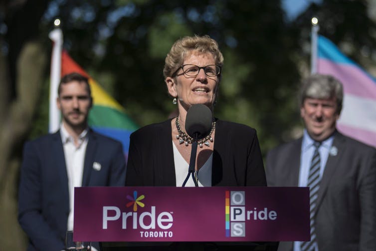 Kathleen Wynne speaks behind a podium that reads Pride.