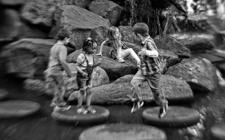 Black-and-white photo of children splashing in rocks.