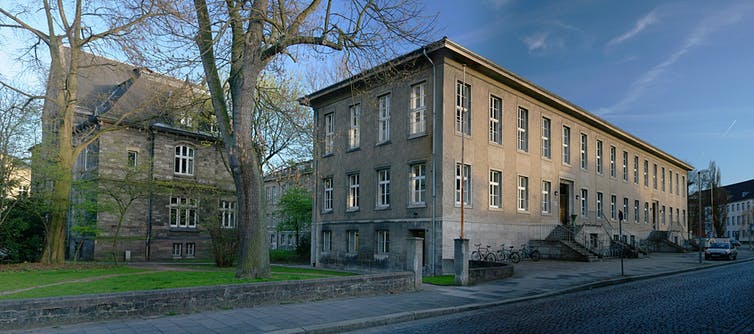 A two-story stone building with trees in the foreground.