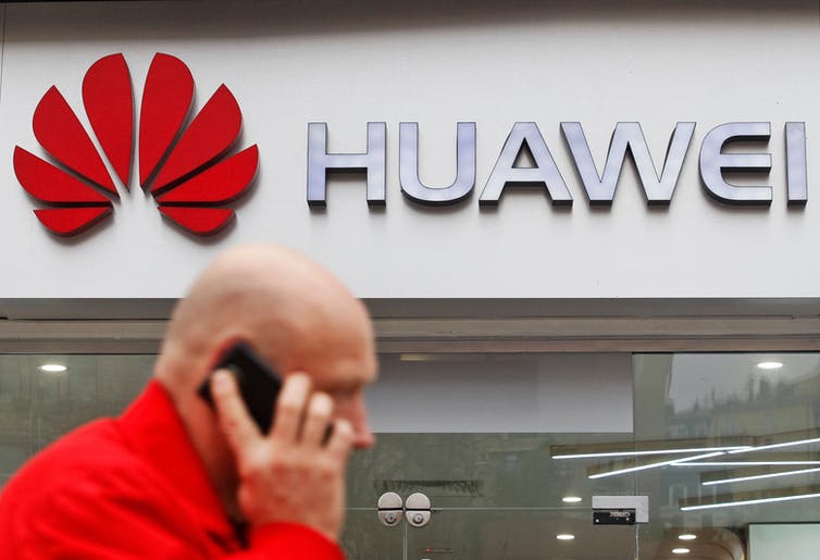 A man on the phone walking in front of a Huawei store