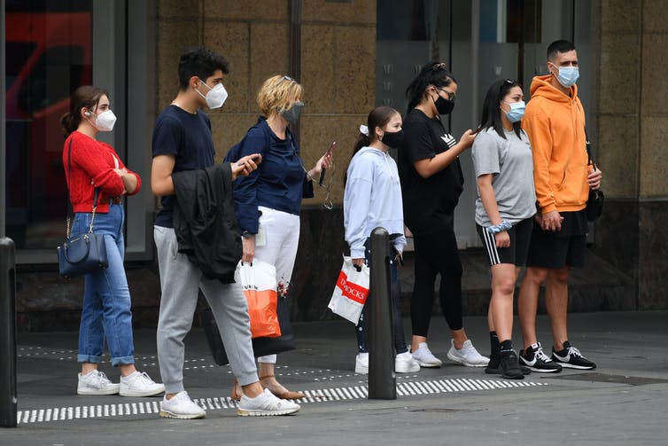 Young people wait at traffic lights to cross the road.