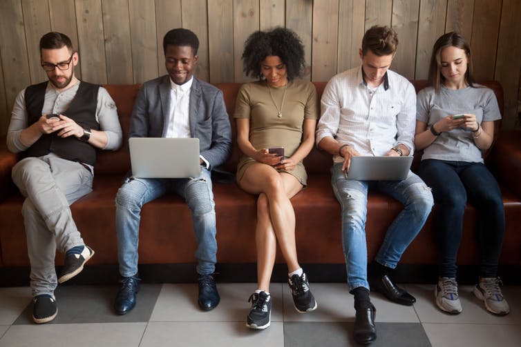 Five people sitting with laptops and mobile phones