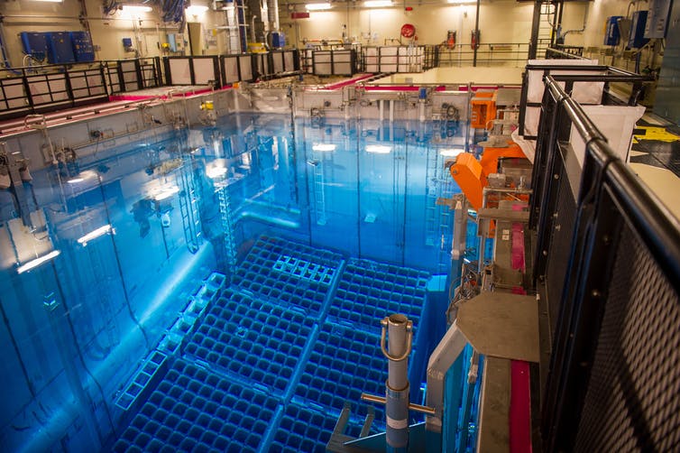 hundreds of square openings lie at the bottom of a large pool of water in an industrial building