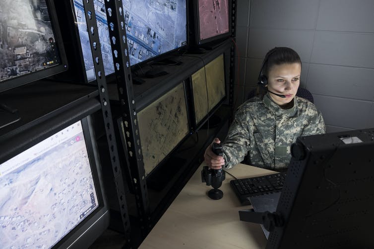 A women in military clothing controls a drone via a computer screen