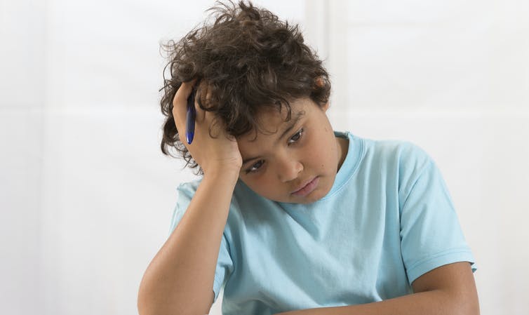 Boy doing homework looking sad