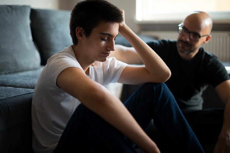 Upset teenage boy talking to older man.