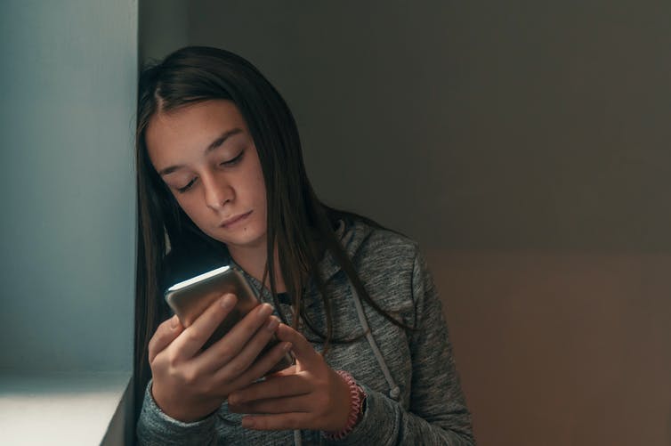 Girl looking at her phone and frowning.