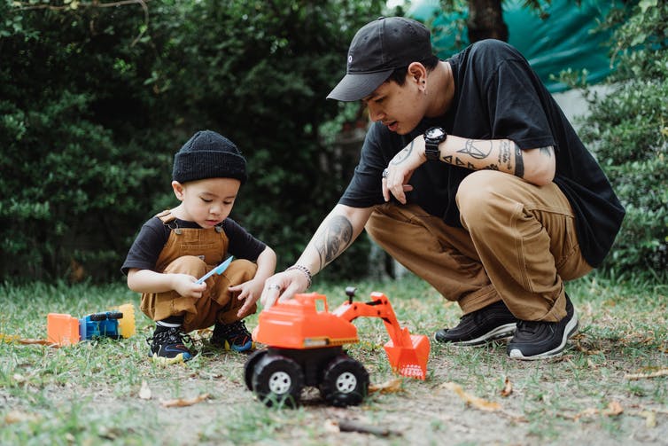 A father seen playing on the ground with his son.