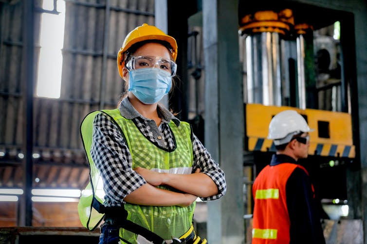 A factory worker in protective gear looks at the camera.