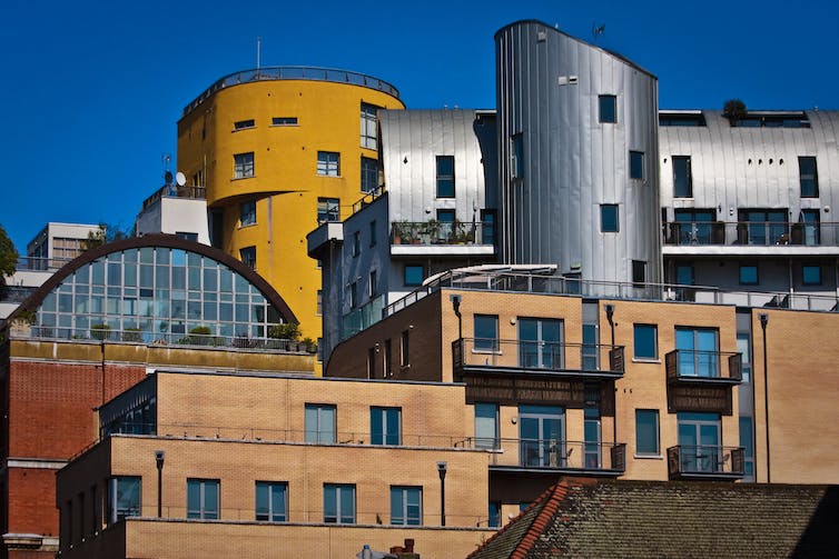 Cluster of nearly-featureless city buildings with competing shapes and colors