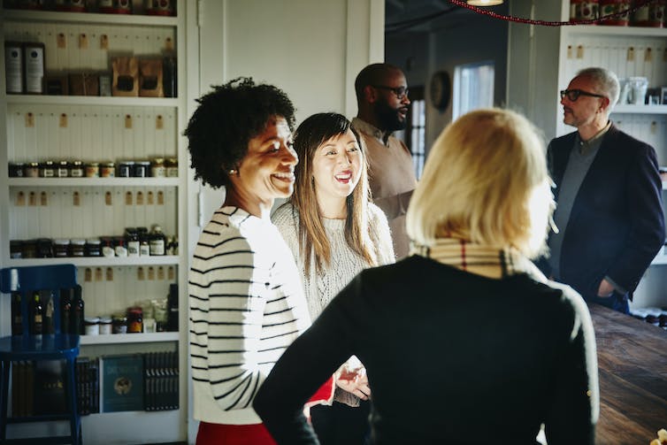 Black woman smiles in conversation with women of other races