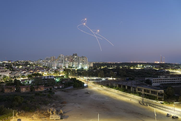 a set of curving light trails in the evening sky above a city