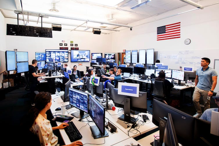 A windowless room filled with people and computer screens