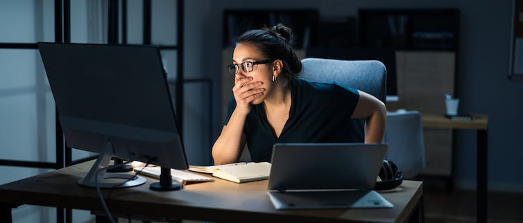 Woman stares at computer screen in shock