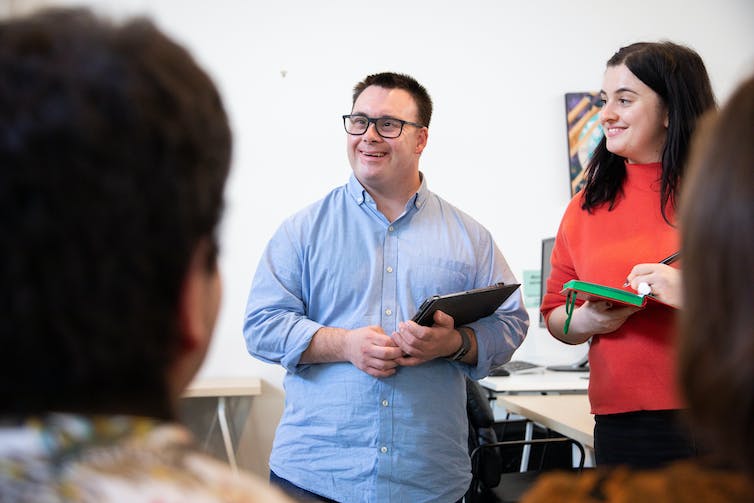 Man stands holding ipad in group of people talking