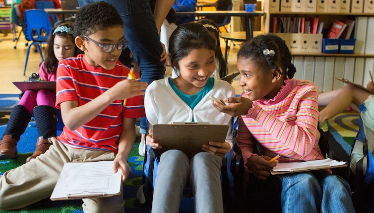 Students seen huddling in a classroom in discussion.