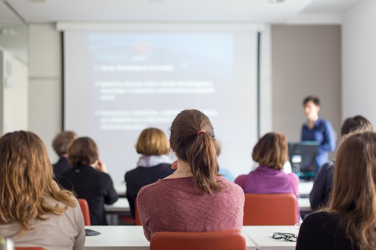 A teacher speaks to a powerpoint display.