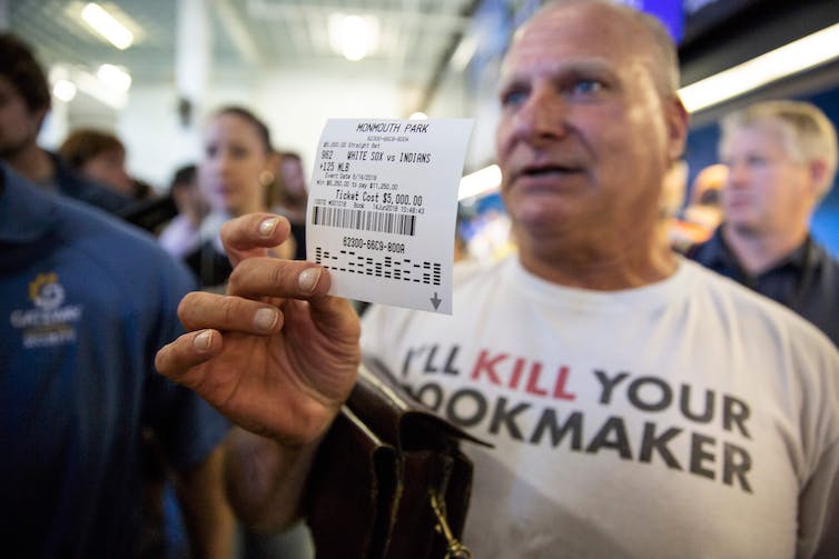 Man holding betting slip.