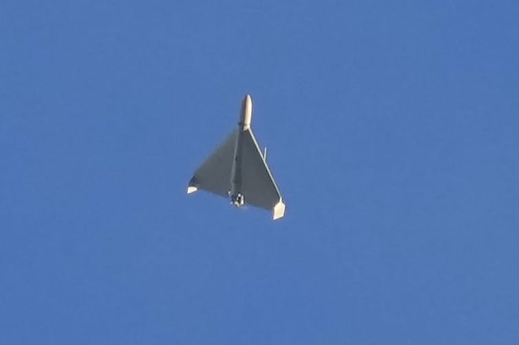 a small light gray delta wing aircraft against a clear blue sky