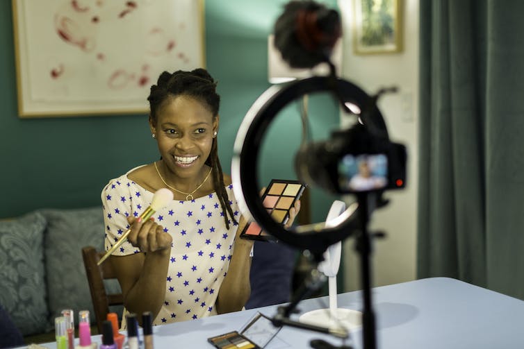 Woman films a video of herself applying makeup.