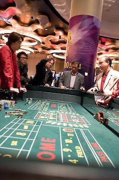 people watch play standing around a casino craps table