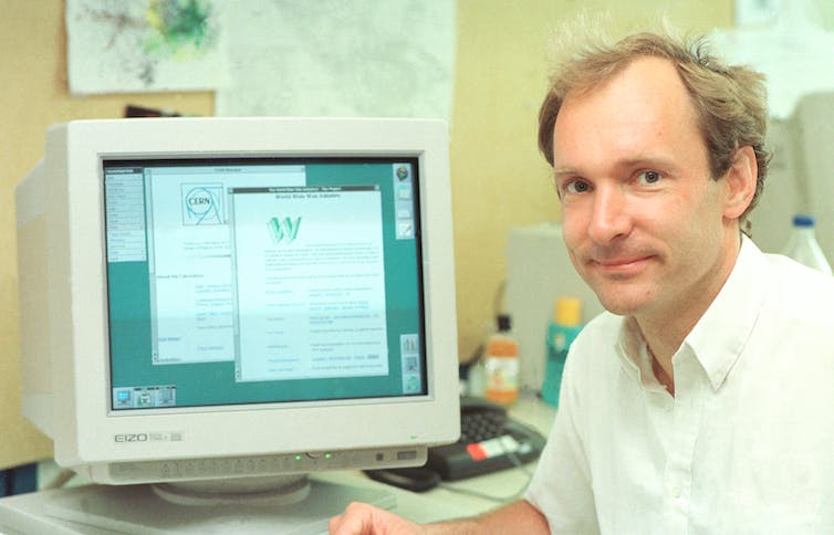 a photograph of a man sitting in front of a cathode ray tube computer monitor