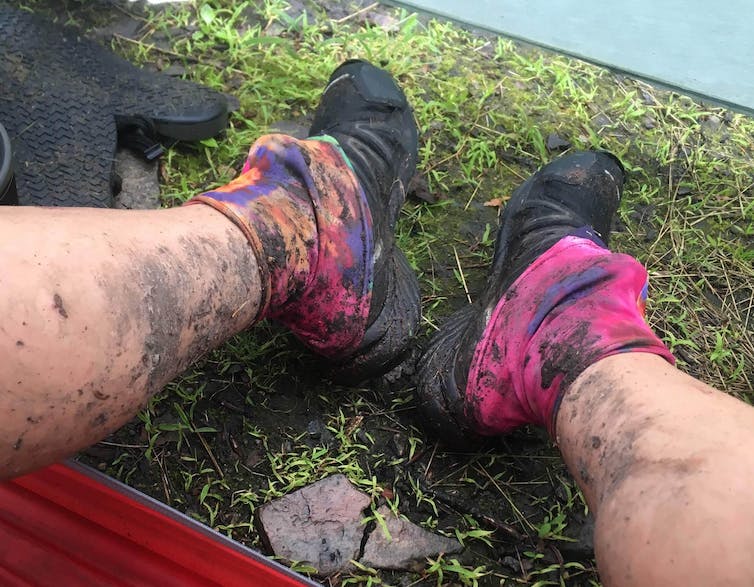 A hiker's feet, with muddy gaiters zipped over shoes.