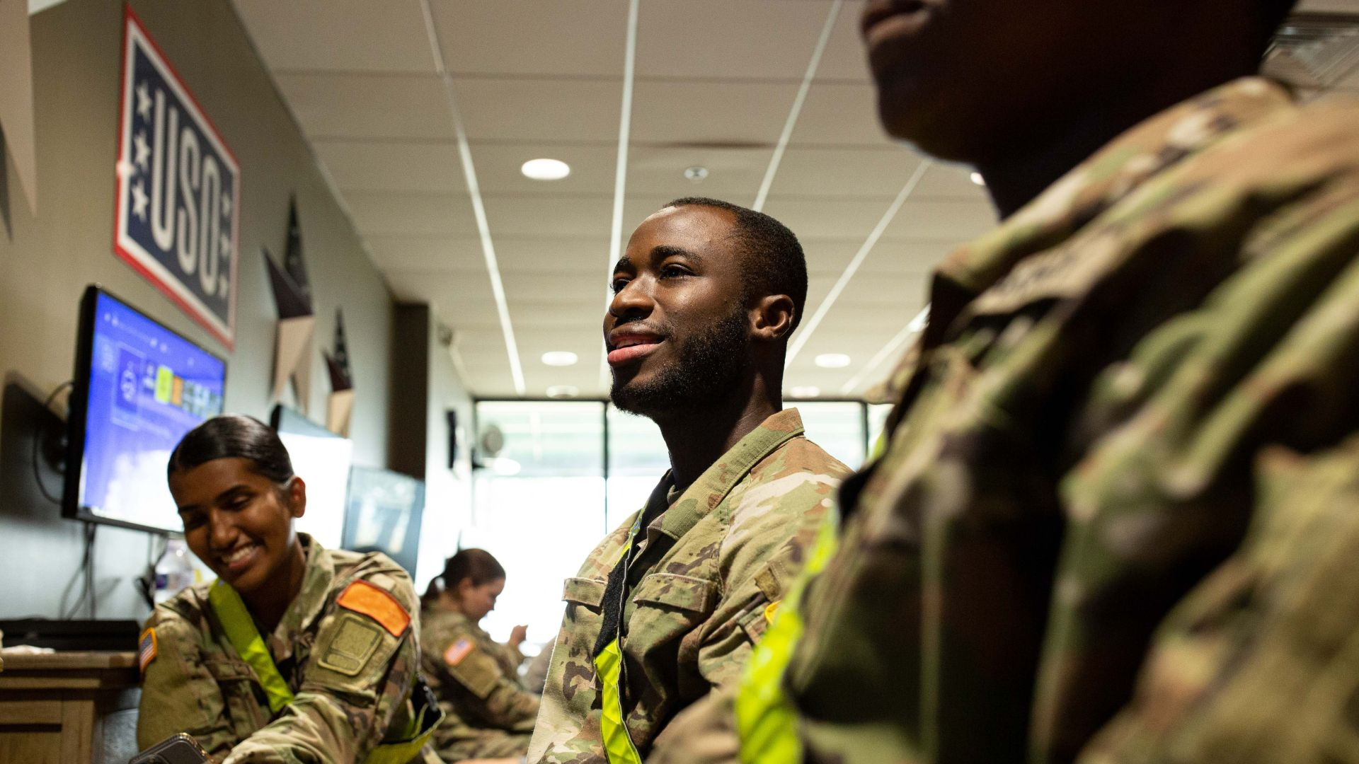 Three people playing games laughing in a USO Center.