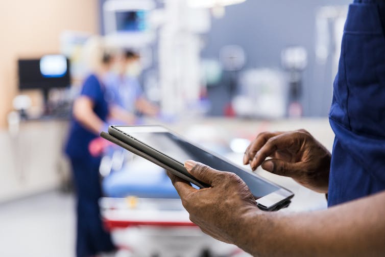 Health care worker looking at tablet in an exam room