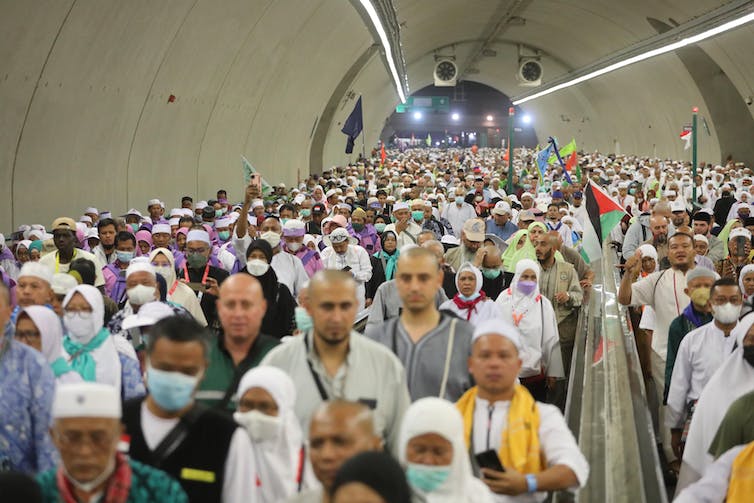 A crowd of people moves through a tunnel.