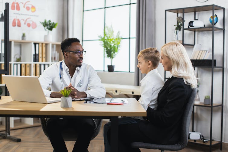 A woman with a child on her lap talking to a doctor